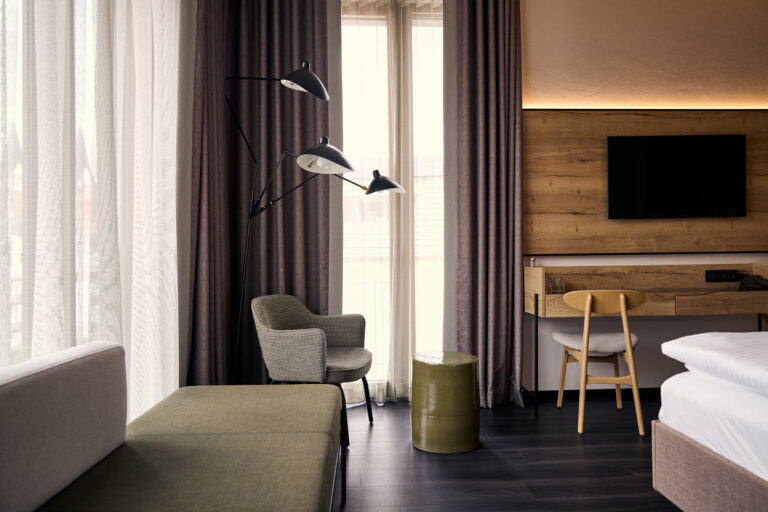 Zimmer mit großem Fenster, einem Stuhl, Arbeitsecke und Bett