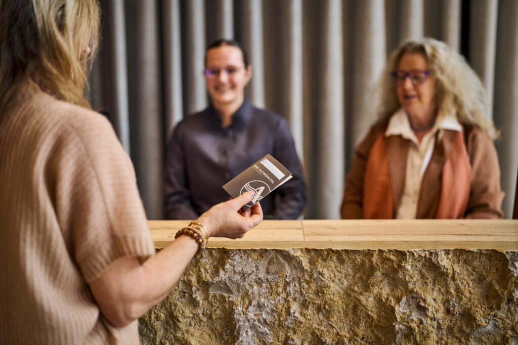 Weiblicher Gast an der Hotelrezeption mit der Zimmerkarte in der Hand