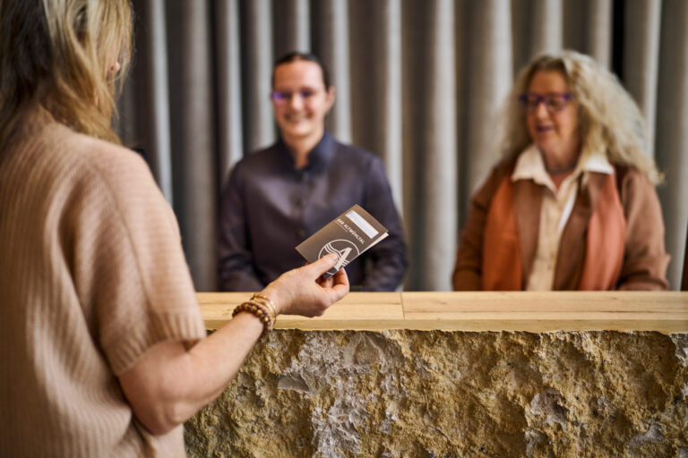 Weiblicher Gast an der Hotelrezeption mit der Zimmerkarte in der Hand